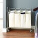 A chrome laundry cart with four white canvas bags.