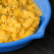 A blue Tablecraft fry pan filled with macaroni and cheese on a counter.