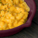 A Tablecraft maroon speckle cast aluminum fry pan filled with macaroni and cheese on a table.