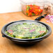 A bowl of salad on a table with a knife.