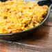 A Tablecraft black cast aluminum skillet filled with food on a table.