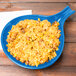 A blue spoon shaped bowl with rice and beans in it on a blue Tablecraft skillet.