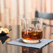 A Libbey room tumbler filled with a drink and ice on a table.