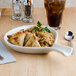 A Tuxton eggshell china fry pan server with food and a drink on a table.