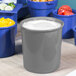 A Tablecraft granite bowl filled with salad dressing on a table with blue bowls of food.