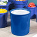 A close-up of a Tablecraft cobalt blue salad dressing bowl with white liquid in it.