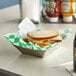 A sandwich in a green check deli wrap on a table.