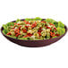 A maroon speckled cast aluminum bowl filled with pasta and lettuce.