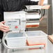 A person using a Robot Coupe stainless steel automatic sieve to make carrot juice.