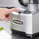 A person using a Waring commercial food processor to chop vegetables.