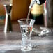 A Thunder Group plastic flared dessert shot glass filled with clear liquid.