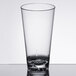 A Thunder Group clear plastic mixing glass on a table.