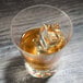 A Thunder Group plastic starburst rocks glass with a drink and ice cubes.