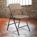 A National Public Seating brown metal folding chair with brown fabric padding.