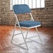 A gray metal National Public Seating folding chair with a blue padded seat.