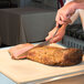 A chef using an Alto-Shaam heated carving station to cut meat on a table.