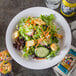 A plate of salad with lettuce, carrots, and crackers on a Carlisle white narrow rim melamine plate.