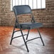 A black metal folding chair with dark midnight blue vinyl padding on the seat and back.