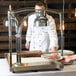 A chef in a white coat using an Alto-Shaam heated carving station to serve food.