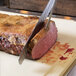 A person using an Alto-Shaam heated carving station to cut a piece of meat.