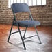 A National Public Seating blue metal folding chair with a blue fabric padded seat.
