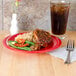 A GET Red Sensation melamine plate with rice, beans, and vegetables on a table with a drink.