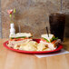 A red GET Red Sensation oval platter with a sandwich and chips on it.