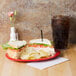 A red oval platter with sandwiches and chips on a table.
