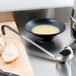 A bowl of soup and a Vollrath Jacob's Pride ladle on a table.