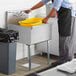 A man in a black apron washing a Steelton commercial utility sink.