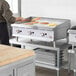 A man using a Cooking Performance Group gas countertop griddle to cook food on a counter.