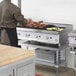 A man cooking food on a Cooking Performance Group gas countertop charbroiler.