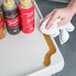 A hand wiping a gray Metro utility cart shelf with a towel.