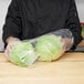 A person holding a plastic bag of lettuce.
