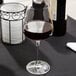 A close-up of a Spiegelau Bordeaux wine glass filled with red wine on a table.