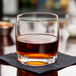 A Spiegelau Rocks glass filled with brown liquid on a table.