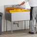 A man standing at a Steelton commercial utility sink in a school kitchen.