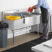 A man washing dishes in a Steelton stainless steel utility sink.