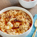 A white bowl of natural maple brown sugar oatmeal with butter and a spoon.