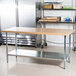 An Advance Tabco wood top work table with a galvanized metal base and undershelf.