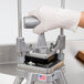 A gloved hand uses a Nemco Easy Chopper to cut produce.