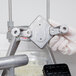 A hand in a glove using a Nemco push block guide assembly to hold a metal piece.