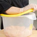 A person wearing gloves holding a Rubbermaid plastic container with a yellow lid.