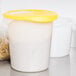 A white Rubbermaid food storage container with a yellow lid full of pasta.