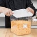 A man holding a Rubbermaid white square polyethylene food storage container with cheese inside.