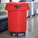 A black Rubbermaid dolly with wheels for black Rubbermaid trash containers.