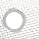 A white circle on a metal grid with round holes.