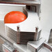 A tomato being sliced by a Nemco tomato slicer plate.