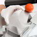 A person using a Nemco tomato slicer push plate to cut a tomato.