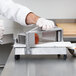 A person using the Nemco Board Conversion Kit to slice carrots on a cutting board.